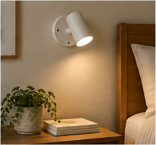 Compact rechargeable wall sconce beside a rental bed