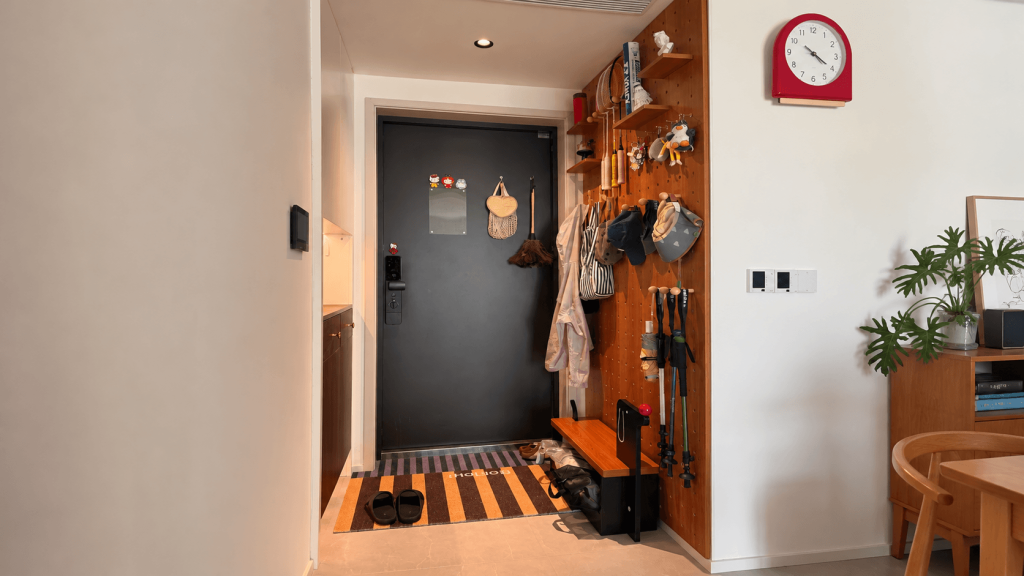Compact entryway bench beneath a pegboard wall holding coats and accessories by the front door.