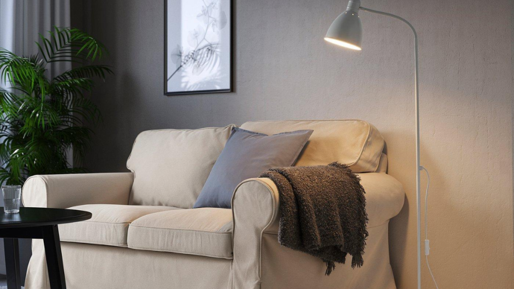 Floor lamp positioned beside a sofa near a wall outlet, showing how furniture placement and cord routing affect lighting choices.