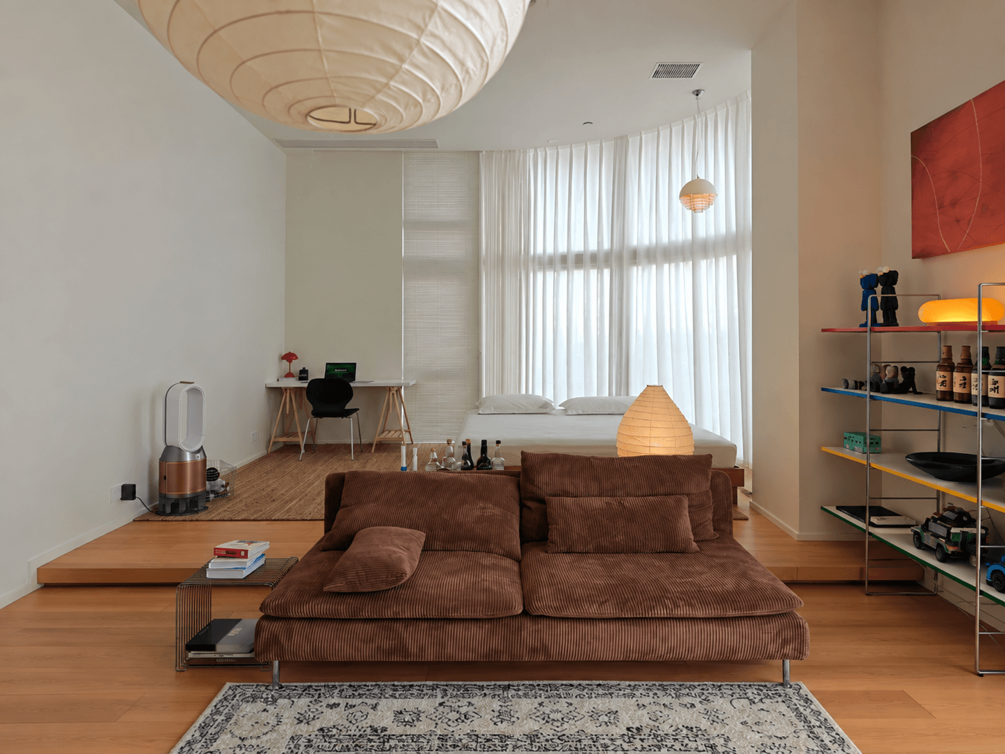 Original photograph of a rental apartment illuminated by several warm light sources around the living and sleeping areas.